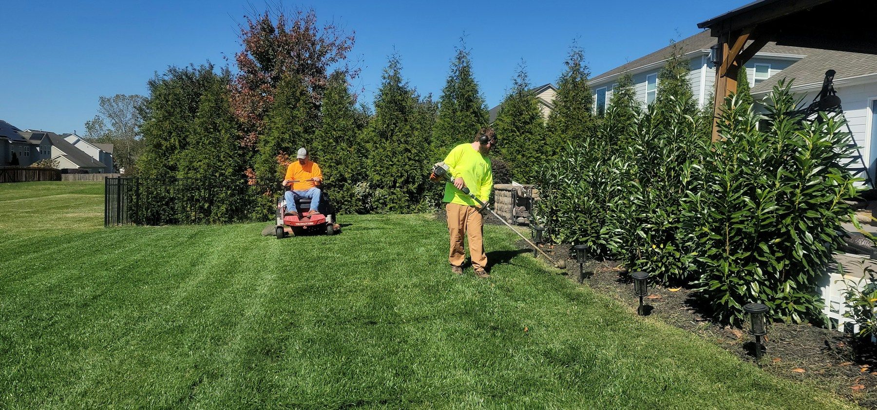 Mowing crew working on a lawn in a residential neighborhood